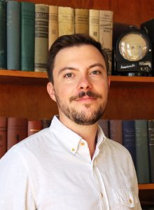 Kyle Webert in front of a bookshelf